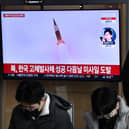 A man watches a television screen showing a news broadcast with file footage of a North Korean missile test, at a railway station in Seoul on December 31, 2022