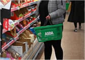 A shopper wearing a protective face covering to combat the spread of the coronavirus, chooses items off the shelves of an Asda supermarket in London on December 14, 2020. - With just over two weeks to go until Britain leaves the EU single market, preparations have been stepped up as fears grow about the impact of customs checks and congested ports. Concern is rising over the supply of perishable fresh fruit and vegetables, much of which is imported from EU countries. (Photo by Daniel LEAL / AFP) (Photo by DANIEL LEAL/AFP via Getty Images)