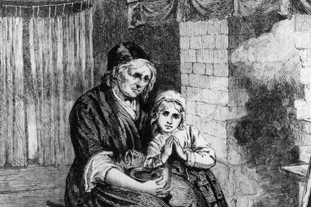 circa 1820:  A mother and child living in poverty sitting close to the fire to keep warm in a bare room. 