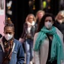 A woman wears a face mask while walking on Oxford Street.