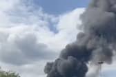 Flames rage through factory as plumes of smoke rise into air.