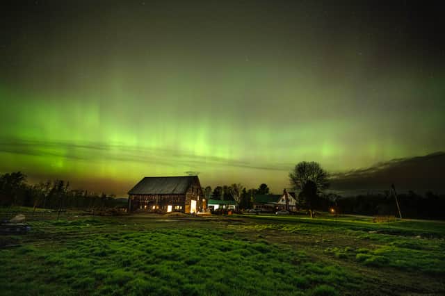 The northern lights fill the sky with green ribbons of electrical charged particles over a barn (Photo by Michael Seamans/Getty Images)