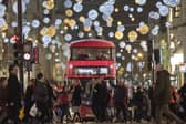 Shoppers cross in front of a London bus as it travels under Christmas lights on Oxford Street in central London in 2017 (Photo: JUSTIN TALLIS/AFP via Getty Images)