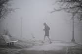 A jogger makes their way through fog on a frosty morning.