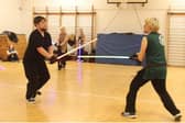 Two people, training with lightsabers