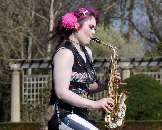 Rachel Ward unicycling while playing the saxophone