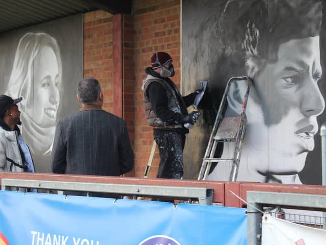 Guillem Balague and Braima Fati watch David Nash put the finishing touches to the new murals at Biggleswade United. Picture by Tia Thorne