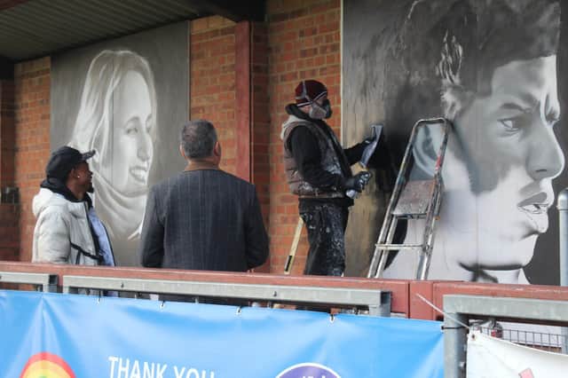 Guillem Balague and Braima Fati watch David Nash put the finishing touches to the new murals at Biggleswade United. Picture by Tia Thorne