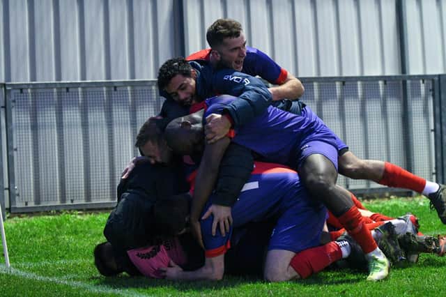 Charlie Black is buried underneath a pile of his Biggleswade United team-mates after he scored what proved to be the crucial winning goal in the vital 1-0 success over relegation rivals ON Chenecks last weekend. Picture courtesy of Cosmin Iftode/Phoro Studio