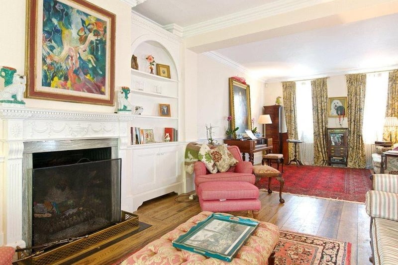 Living room: retained period features include moulded coving and a dado rail, and an open fireplace with a fluted pilaster painted wood mantel, with alcoves either side fitted with bowed bookshelves.