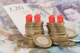 File photo of model houses on a pile of coins and bank notes.
