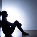 Stock image of a person sitting alone in a dark room. Credit: Getty/KatarzynaBialasiewicz