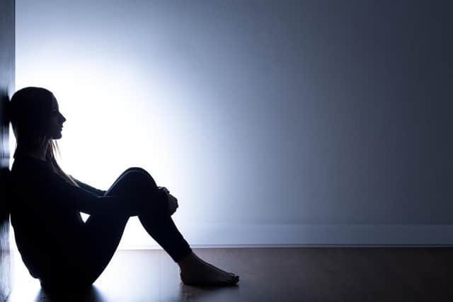 Stock image of a person sitting alone in a dark room. Credit: Getty/KatarzynaBialasiewicz