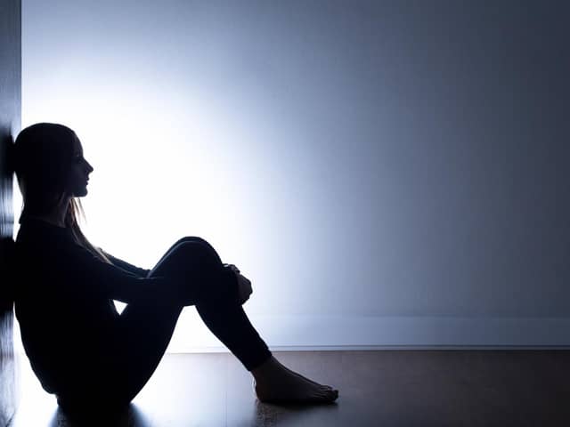 Stock image of a person sitting alone in a dark room. Credit: Getty/KatarzynaBialasiewicz