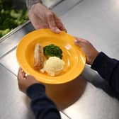 A school chef serves cooked hot dinner to a student (Photo by DANIEL LEAL/AFP via Getty Images)