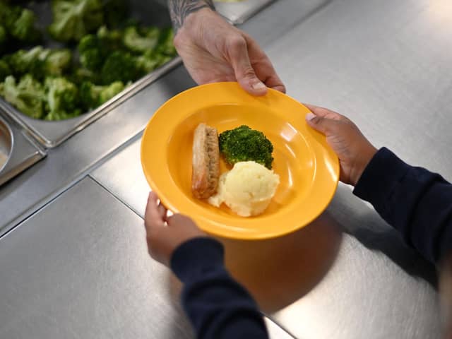A school chef serves cooked hot dinner to a student (Photo by DANIEL LEAL/AFP via Getty Images)