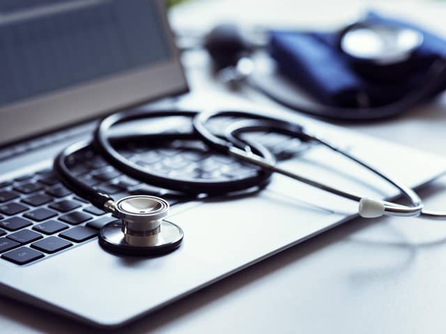 Stethoscope on laptop keyboard in doctor surgery with blood pressure monitor
