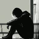 File photo of a teenage boy sitting alone in the dark