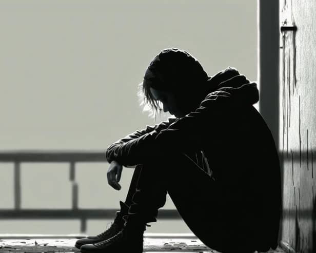 File photo of a teenage boy sitting alone in the dark