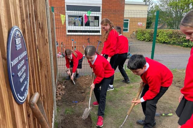 Pupils burying time capsules next to the staff wellbeing garden at Robert Bloomfield Academy.