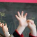 File photo of children raising their hands in class (Photo by Christopher Furlong/Getty Images)