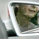 File photo:  A woman, reflected in a rear-view mirror, talks on a mobile phone while driving in traffic (Photo by Ian Waldie/Getty Images)