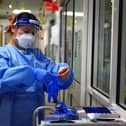 File photo - a nurse puts on PPE in a ward for Covid patients