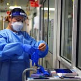 File photo - a nurse puts on PPE in a ward for Covid patients
