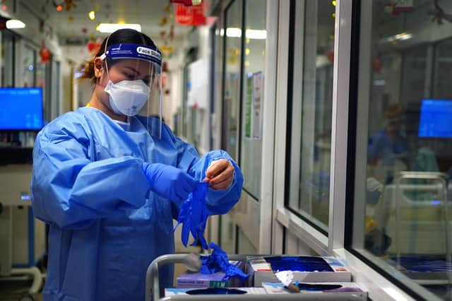 File photo - a nurse puts on PPE in a ward for Covid patients
