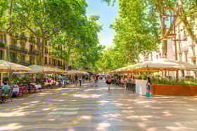 Tourists walk past sidewalk cafes on the famous La Rambla street. Picture: Kirk Fisher, Adobe Stock
