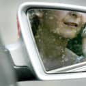 File photo:  A woman, reflected in a rear-view mirror, talks on a mobile phone while driving in traffic (Photo by Ian Waldie/Getty Images)