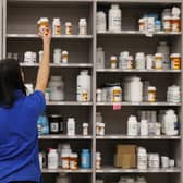 A pharmacy technician grabs a bottle of drugs off a shelf  (Photo by George Frey/Getty Images)