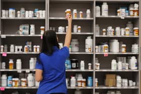 A pharmacy technician grabs a bottle of drugs off a shelf  (Photo by George Frey/Getty Images)