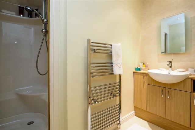 Here is the en suite bathroom to the master bedroom. Compact, it features a sauna shower, top-mounted sink with vanity surround, low-flush WC, tiled floor and chrome heated towel-rail.