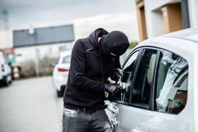A person breaking into a car. Photo: Adobe Stock