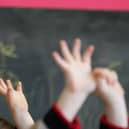 Children wave their hands in a classroom (Photo by Christopher Furlong/Getty Images).