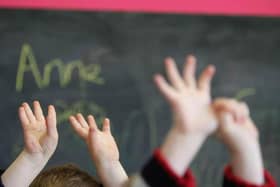 Children wave their hands in a classroom (Photo by Christopher Furlong/Getty Images).