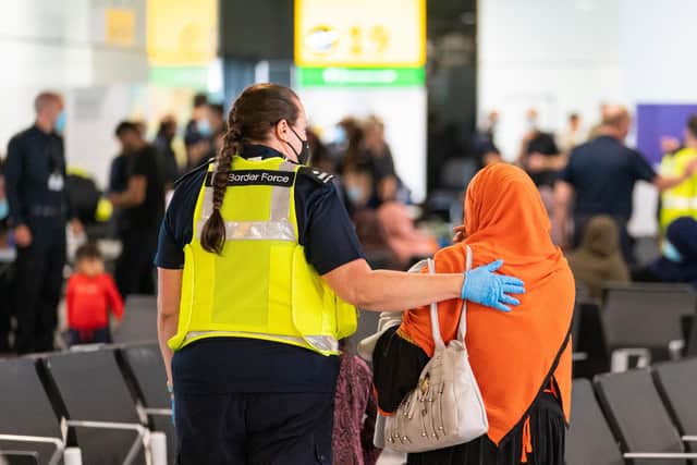 File photo: A member of Border Force staff assists a female evacuee as refugees arrive from Afghanistan at Heathrow Airport. (Photo by Dominic Lipinski - WPA Pool/Getty Images)
