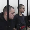 Two British citizens Aiden Aslin, left, and Shaun Pinner, right, and Moroccan Saaudun Brahim, center, sit behind bars in a courtroom in Donetsk, in the territory which is under the Government of the Donetsk People's Republic control, eastern Ukraine, Thursday, June 9, 2022. The two British citizens and a Moroccan have been sentenced to death by pro-Moscow rebels in eastern Ukraine for fighting on Ukraine's side. The three men fought alongside Ukrainian troops and surrendered to Russian forces weeks ago. (AP Photo)