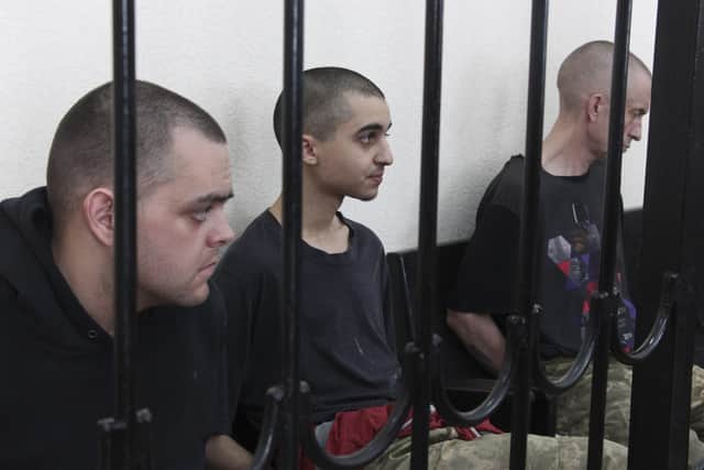 Two British citizens Aiden Aslin, left, and Shaun Pinner, right, and Moroccan Saaudun Brahim, center, sit behind bars in a courtroom in Donetsk, in the territory which is under the Government of the Donetsk People's Republic control, eastern Ukraine, Thursday, June 9, 2022. The two British citizens and a Moroccan have been sentenced to death by pro-Moscow rebels in eastern Ukraine for fighting on Ukraine's side. The three men fought alongside Ukrainian troops and surrendered to Russian forces weeks ago. (AP Photo)