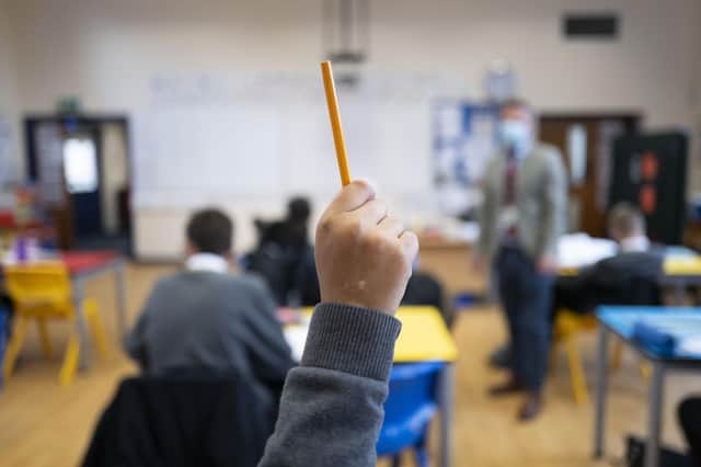 A pupil raises their hand during a lesson (Photo by Matthew Horwood/Getty Images)