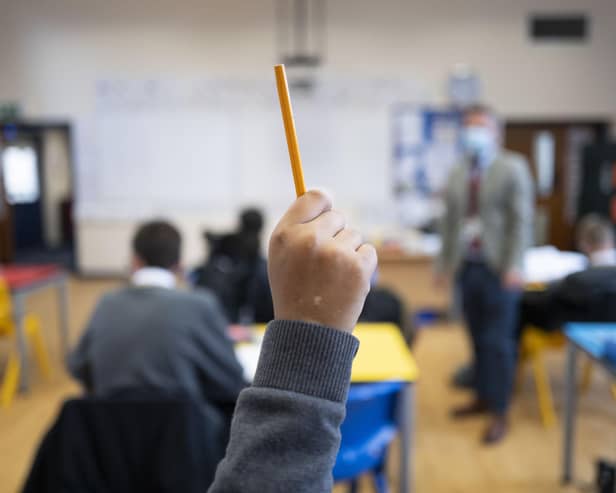 A pupil raises their hand during a lesson (Photo by Matthew Horwood/Getty Images)