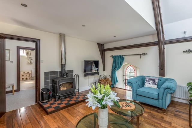The spacious lounge features arched stained glass windows and log burning stove