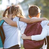 School friends a boy and two girls with school backpacks on their backs walk after class