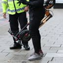 An e-scooter rider is stopped by a police officer. Picture: Yui Mok/PA