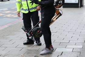 An e-scooter rider is stopped by a police officer. Picture: Yui Mok/PA