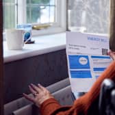 File photo of an elderly woman standing in front of a radiator holding an energy bill.