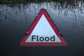 A flood warning road sign on a partially submerged road (Photo by Oli Scarff/Getty Images)