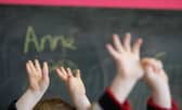 File photo of children raising their hands in class (Photo by Christopher Furlong/Getty Images)