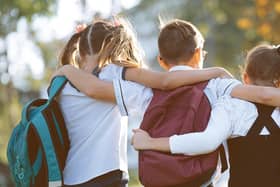 School friends a boy and two girls with school backpacks on their backs walk after class